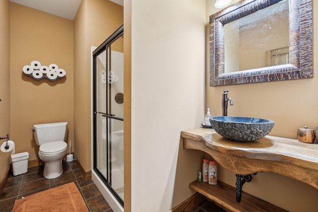 bathroom featuring toilet, a shower with door, tile patterned floors, and sink