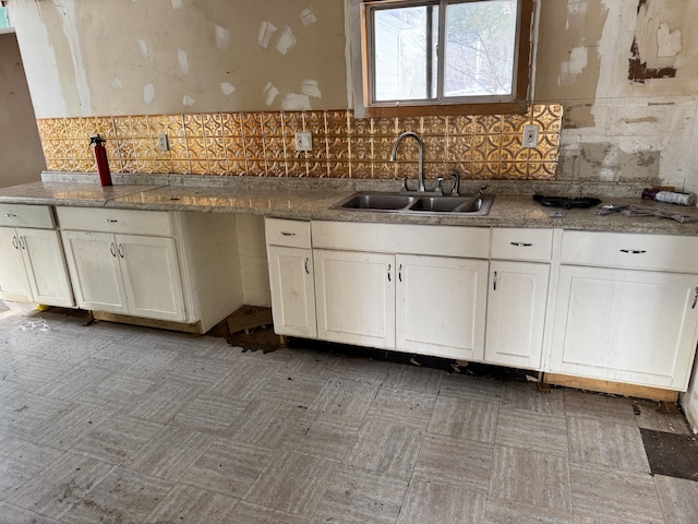 kitchen with sink, white cabinetry, stone counters, and backsplash