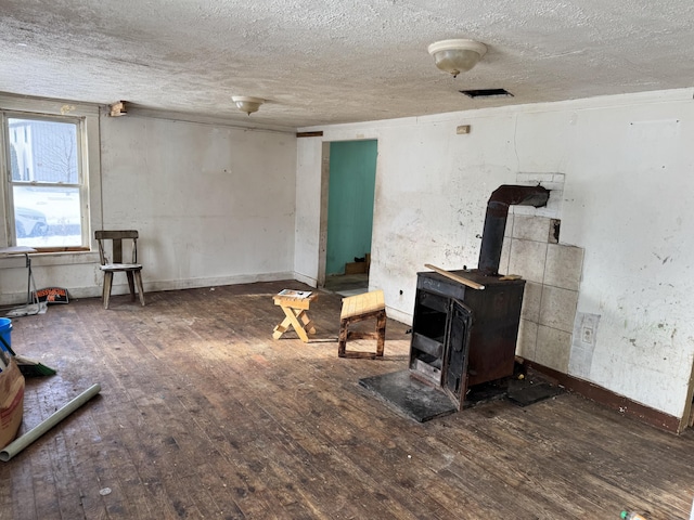 living room featuring a textured ceiling, dark hardwood / wood-style floors, and a wood stove