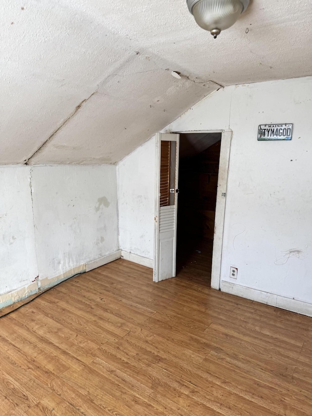 bonus room featuring wood-type flooring, a textured ceiling, and vaulted ceiling