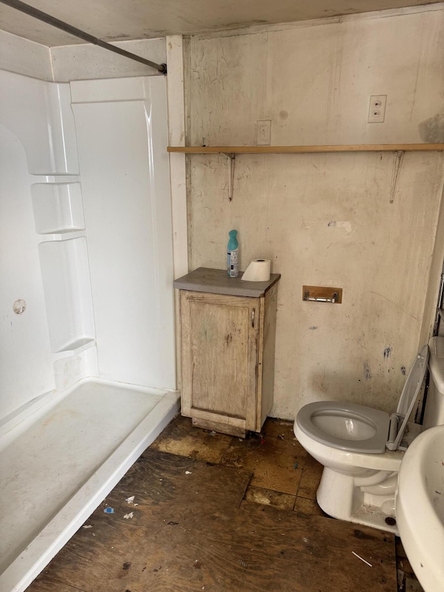 bathroom featuring toilet, a shower, and sink