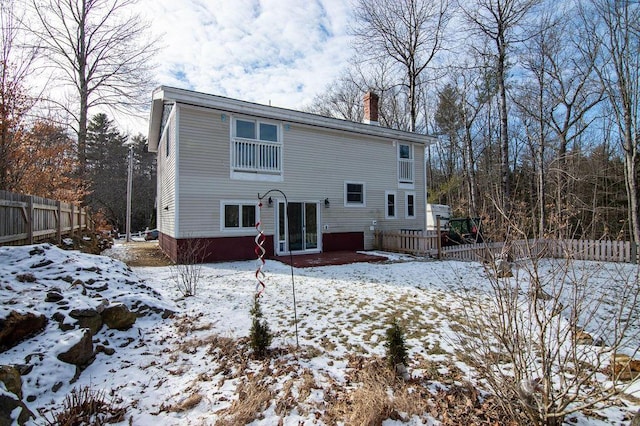 snow covered back of property with a wooden deck