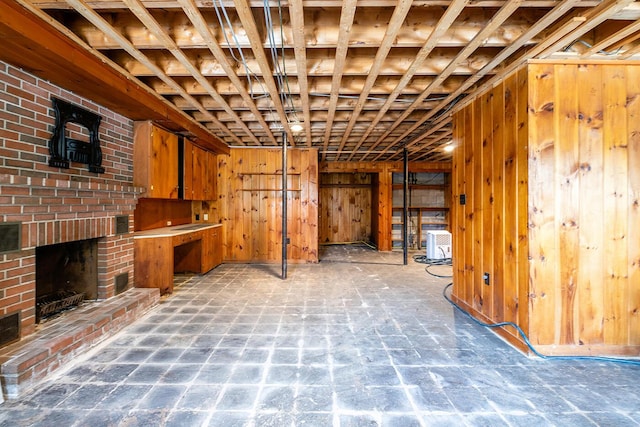 basement featuring a brick fireplace and wood walls