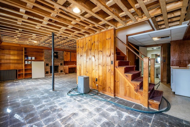 basement featuring washer / clothes dryer, wooden walls, and a fireplace