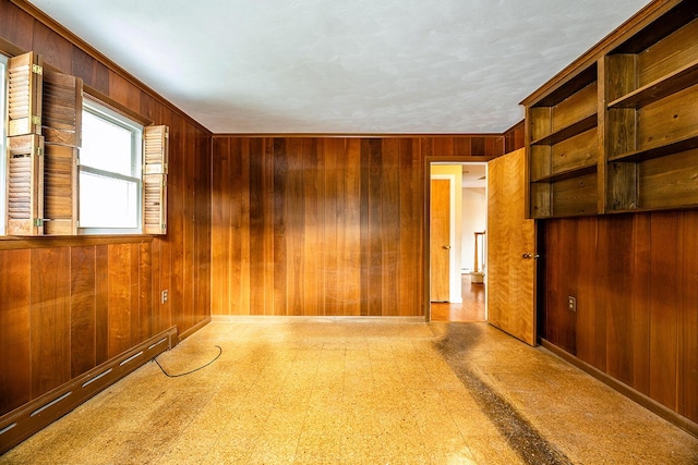 unfurnished room featuring wooden walls and a baseboard heating unit