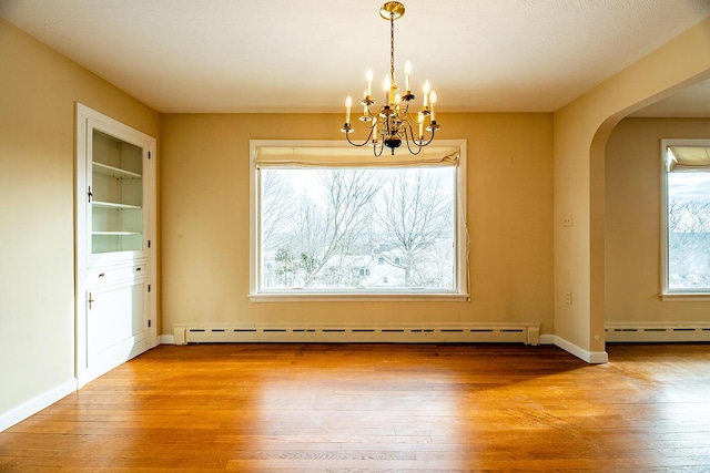 unfurnished dining area with a chandelier, baseboard heating, and light hardwood / wood-style floors