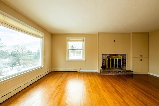 unfurnished living room featuring a fireplace, baseboard heating, and hardwood / wood-style flooring