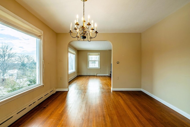 spare room featuring baseboard heating, hardwood / wood-style flooring, and a notable chandelier