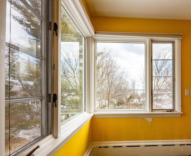 unfurnished sunroom featuring a baseboard heating unit and a healthy amount of sunlight