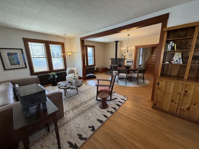 living room with radiator, hardwood / wood-style flooring, a healthy amount of sunlight, and a wood stove