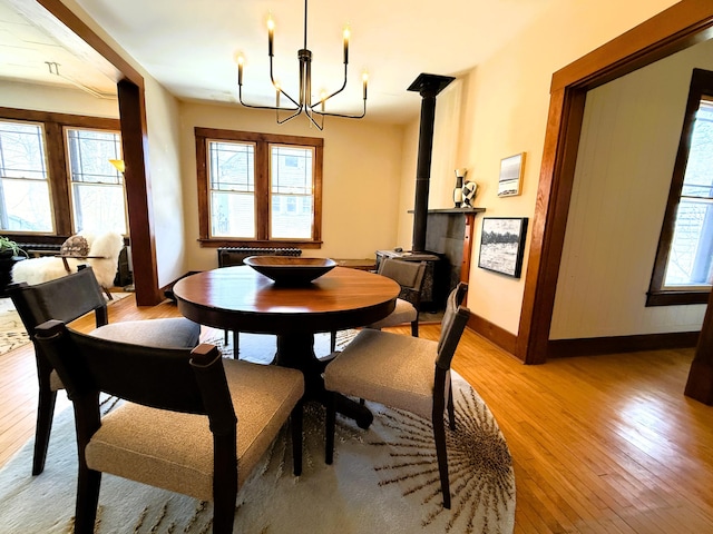 dining space featuring light wood-type flooring, a chandelier, a wood stove, and plenty of natural light