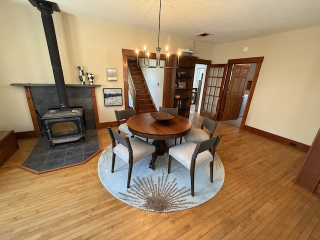 dining space featuring an inviting chandelier, light hardwood / wood-style flooring, and a wood stove