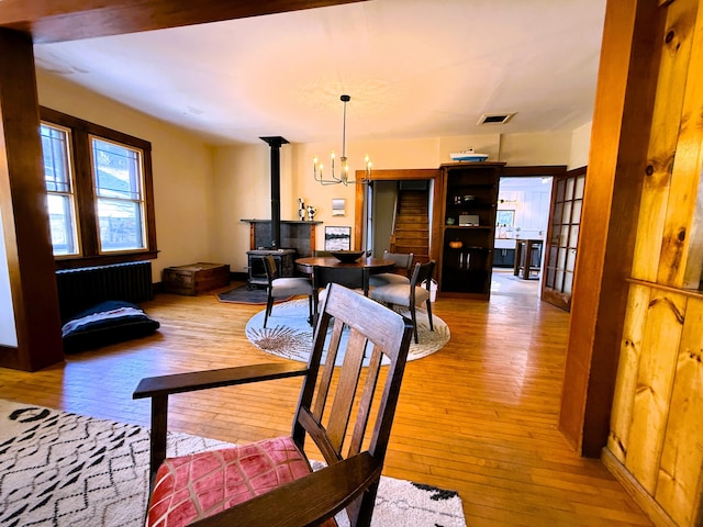 dining space with a notable chandelier, hardwood / wood-style floors, a wood stove, and radiator