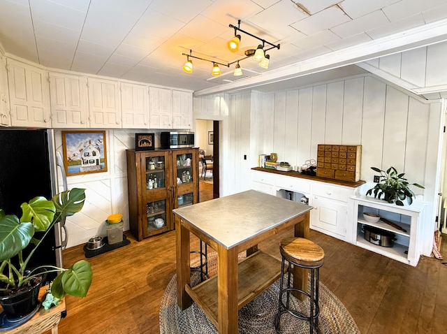 kitchen featuring white cabinets, stainless steel appliances, track lighting, and dark hardwood / wood-style flooring