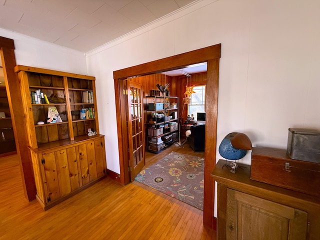 hallway with light wood-type flooring and crown molding