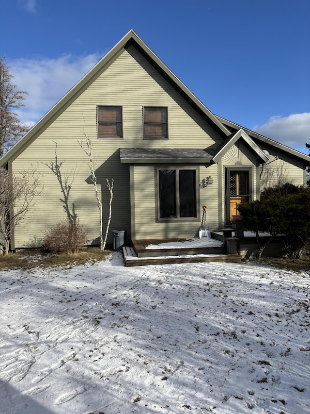 snow covered back of property with a deck