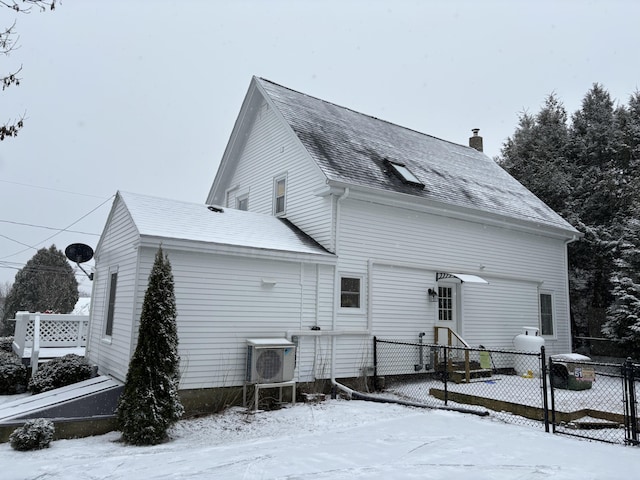 snow covered house featuring ac unit