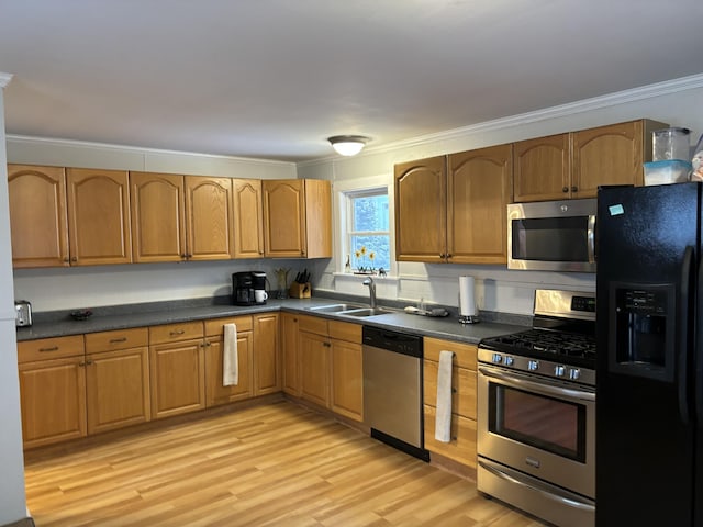 kitchen with appliances with stainless steel finishes, sink, crown molding, and light hardwood / wood-style flooring