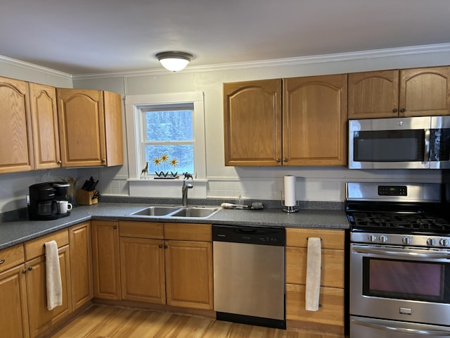 kitchen with sink, ornamental molding, stainless steel appliances, and light wood-type flooring