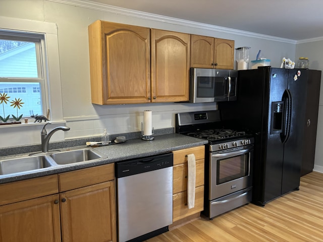 kitchen featuring stainless steel appliances, crown molding, light hardwood / wood-style floors, and sink