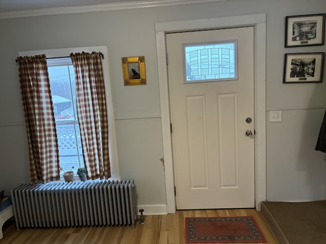 entrance foyer featuring radiator heating unit, crown molding, and light hardwood / wood-style flooring