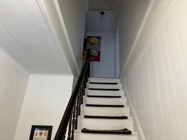 staircase featuring wooden walls