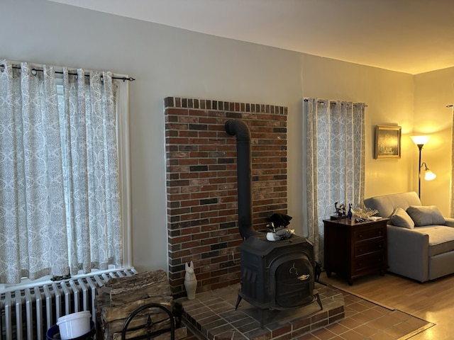 living room with radiator, a wood stove, and hardwood / wood-style floors