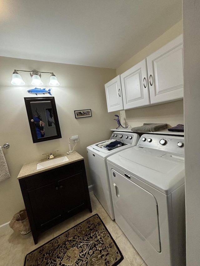 clothes washing area with washer and clothes dryer, sink, light tile patterned floors, and cabinets