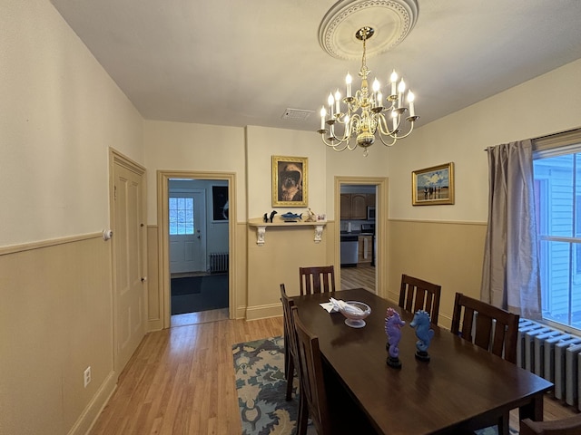 dining area with light hardwood / wood-style floors, radiator, and a chandelier