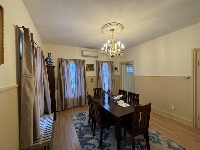 dining area featuring a wall mounted AC, a chandelier, and hardwood / wood-style floors