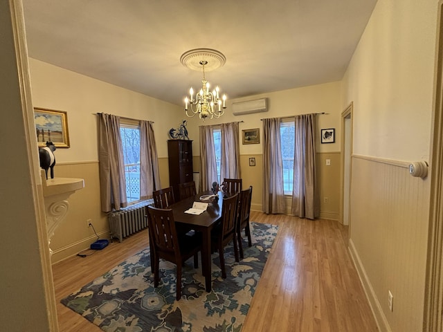 dining space with radiator, an inviting chandelier, light hardwood / wood-style flooring, and a wall mounted air conditioner