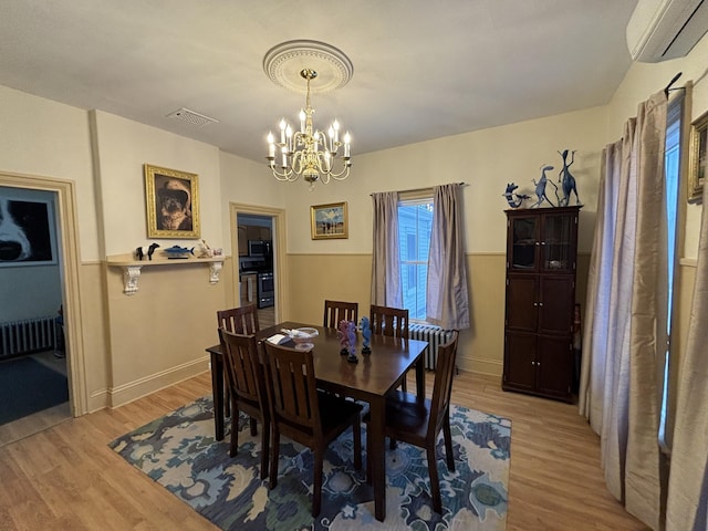 dining area featuring a notable chandelier, radiator, light wood-type flooring, and a wall mounted air conditioner