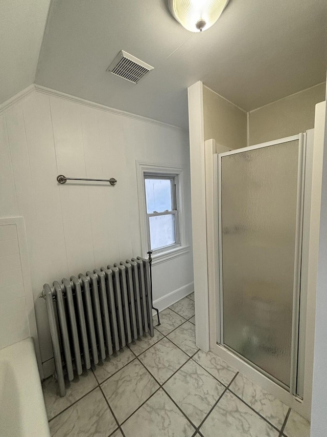 bathroom featuring a shower with shower door, radiator, and vaulted ceiling