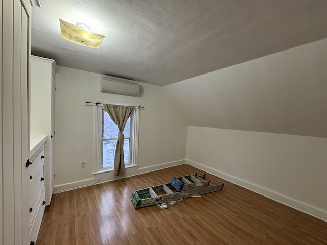 bonus room with wood-type flooring, lofted ceiling, and a wall mounted air conditioner