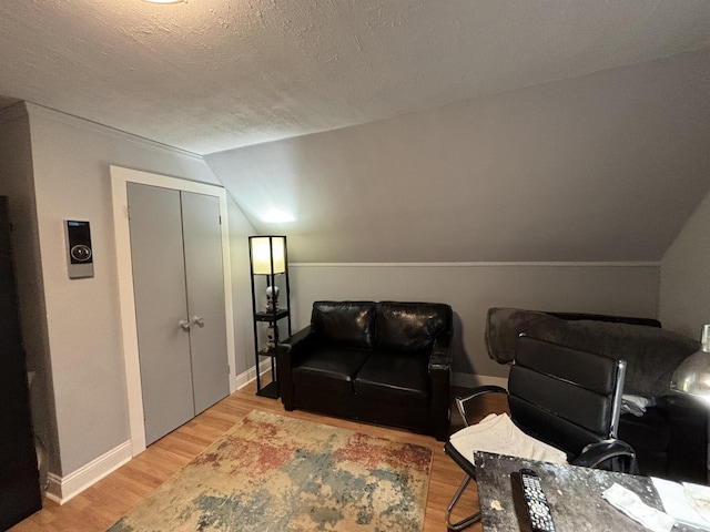 living room with hardwood / wood-style floors, lofted ceiling, and a textured ceiling