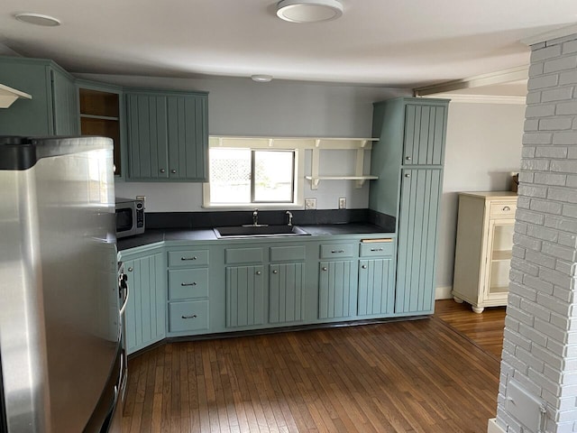 kitchen with stainless steel appliances, green cabinetry, sink, and dark wood-type flooring