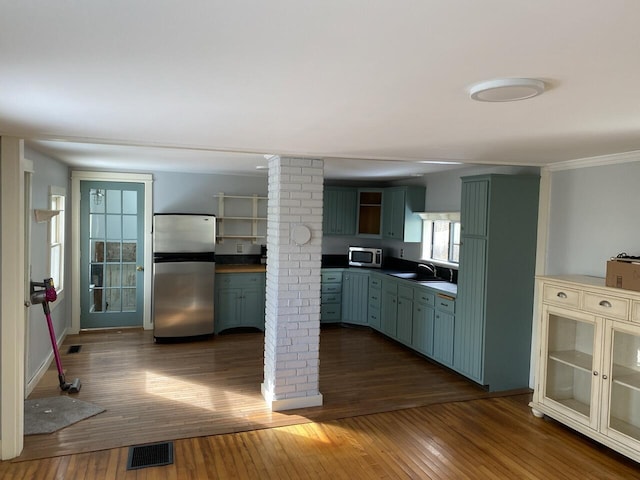 kitchen featuring stainless steel appliances, green cabinetry, decorative columns, dark hardwood / wood-style flooring, and sink