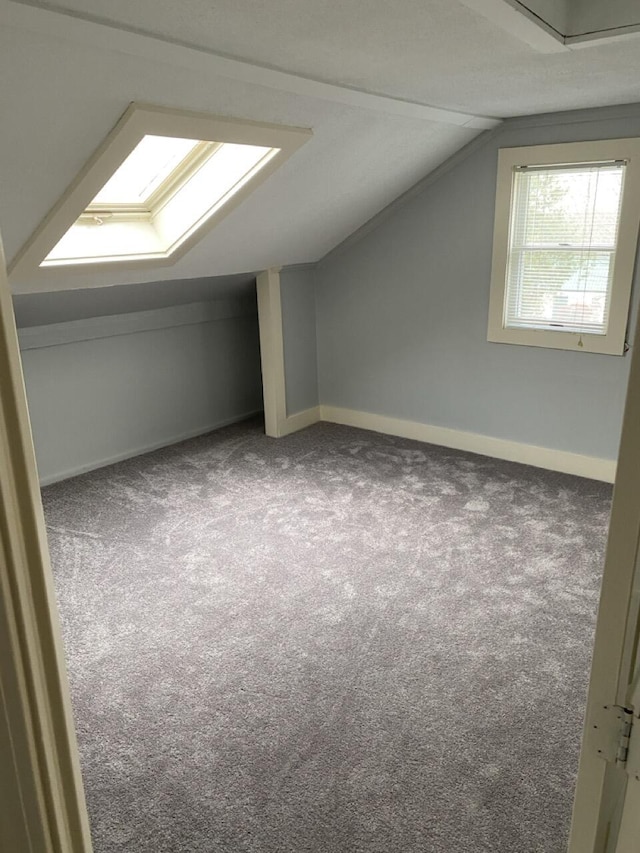 bonus room with lofted ceiling with skylight and carpet