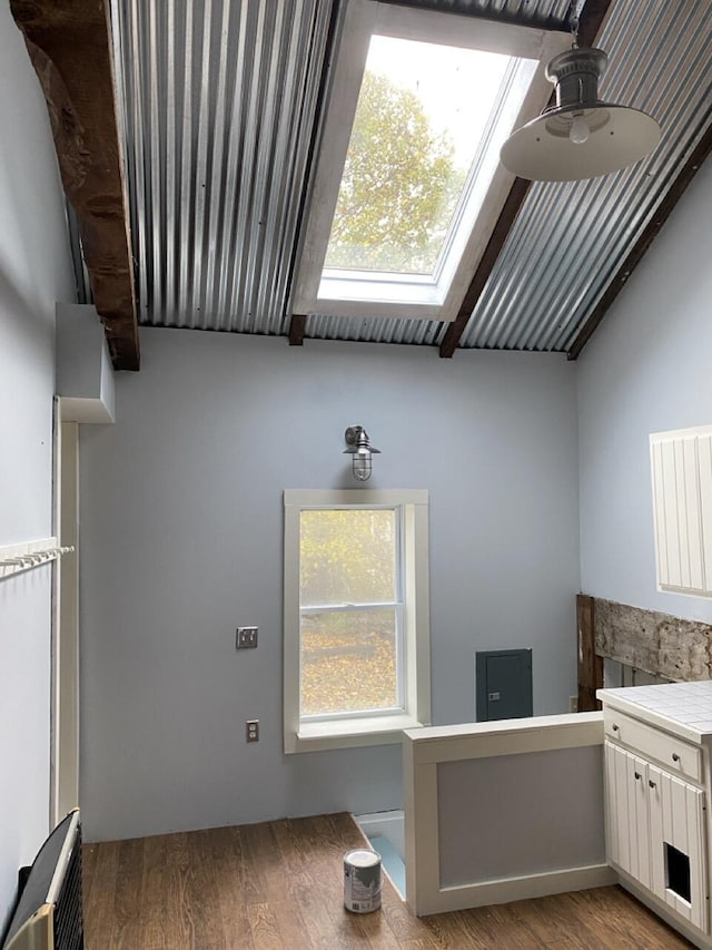 kitchen featuring lofted ceiling, white cabinets, light hardwood / wood-style flooring, and a healthy amount of sunlight