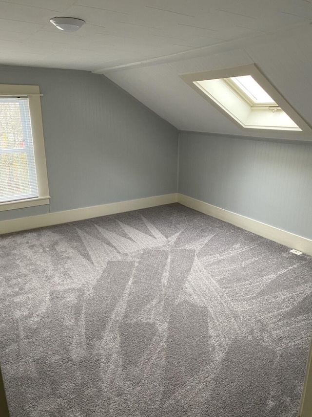 additional living space featuring carpet floors and lofted ceiling with skylight