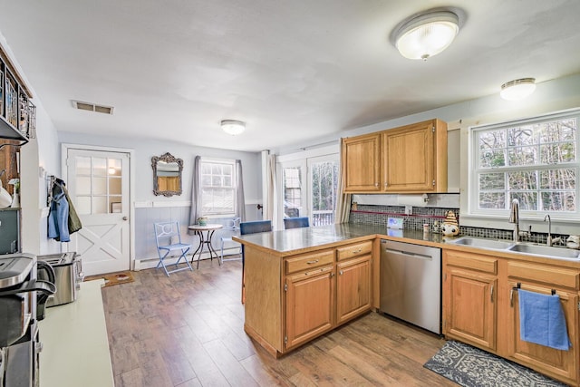 kitchen with a baseboard heating unit, stainless steel dishwasher, kitchen peninsula, wood-type flooring, and sink