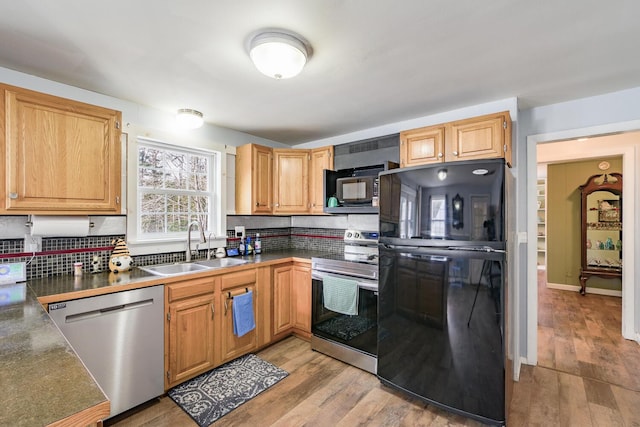 kitchen featuring black appliances, light wood-type flooring, sink, and decorative backsplash