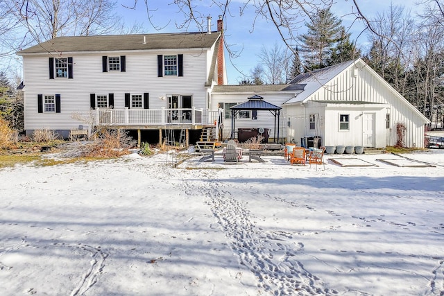 snow covered back of property with a deck and a gazebo