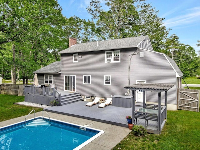 rear view of property featuring a lawn, a pergola, and a pool side deck