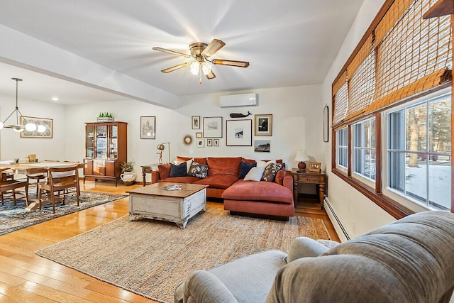 living room featuring ceiling fan with notable chandelier, a baseboard heating unit, light wood-type flooring, and a wall mounted AC