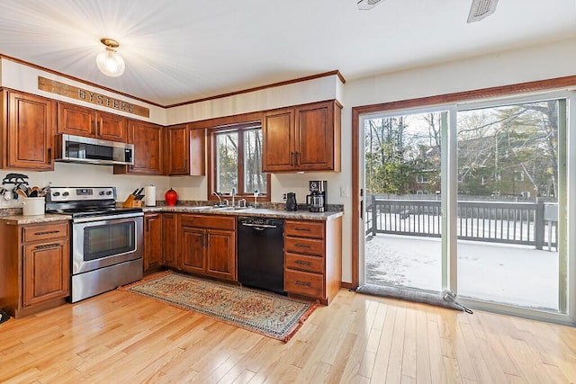 kitchen with sink, stainless steel appliances, light hardwood / wood-style floors, and light stone countertops