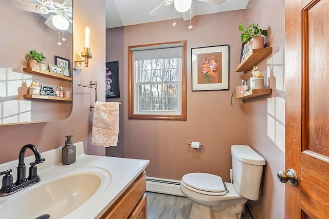 bathroom featuring toilet, vanity, baseboard heating, and hardwood / wood-style floors