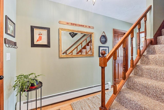 staircase with wood-type flooring and a baseboard radiator