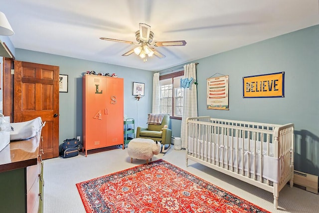 carpeted bedroom featuring ceiling fan and a nursery area