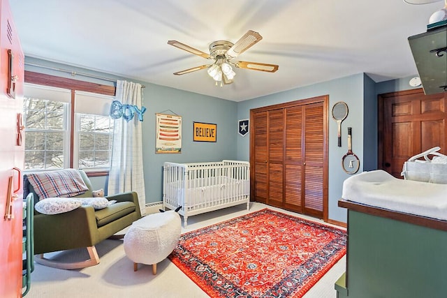 bedroom featuring a crib, a closet, and ceiling fan